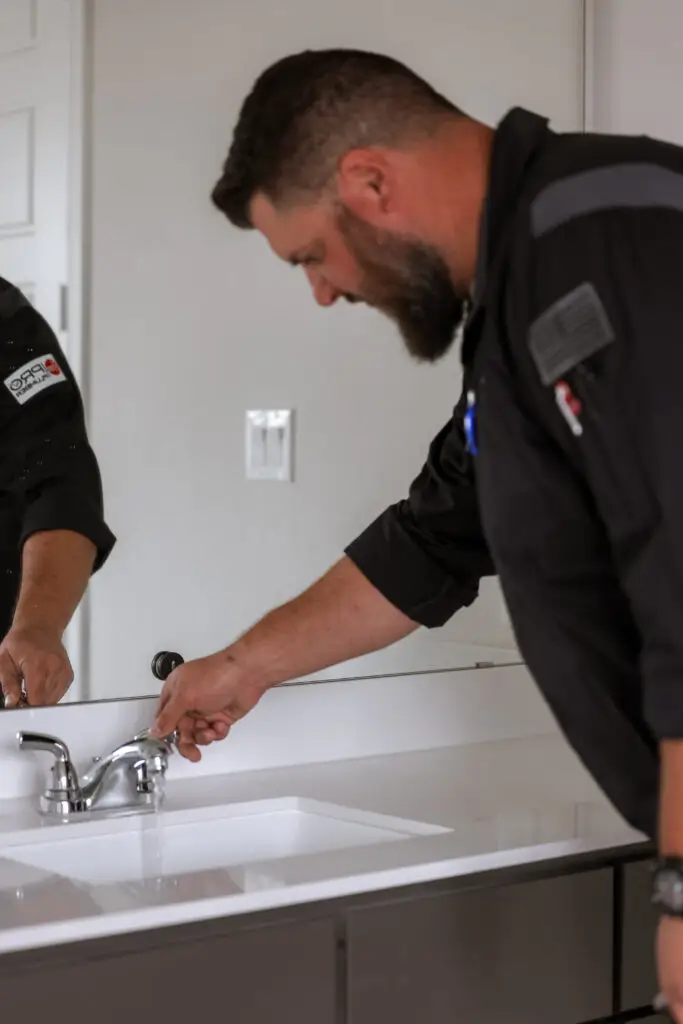 Plumber fixing a leaky kitchen faucet