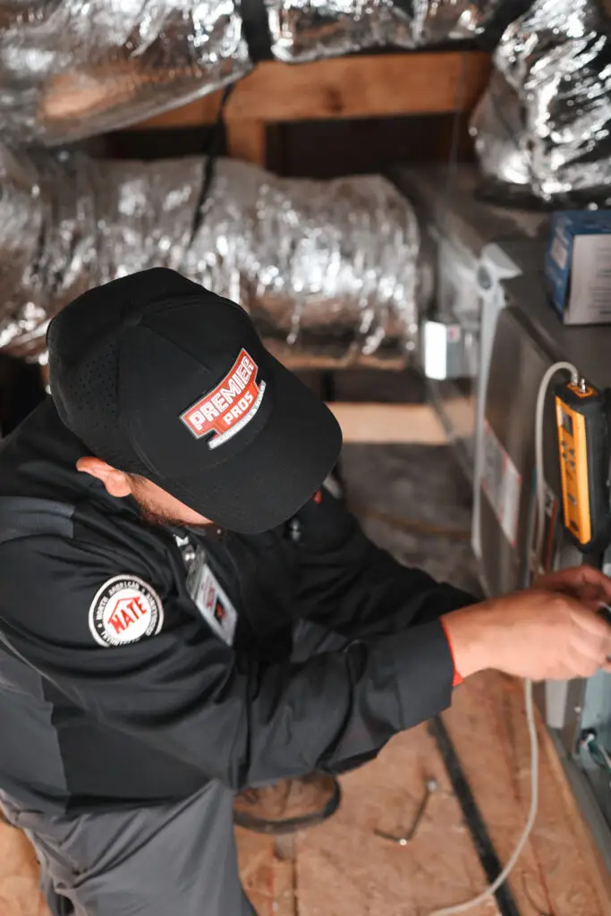 A friendly Premier Pros technician installing a new air conditioner unit in a San Antonio home."
