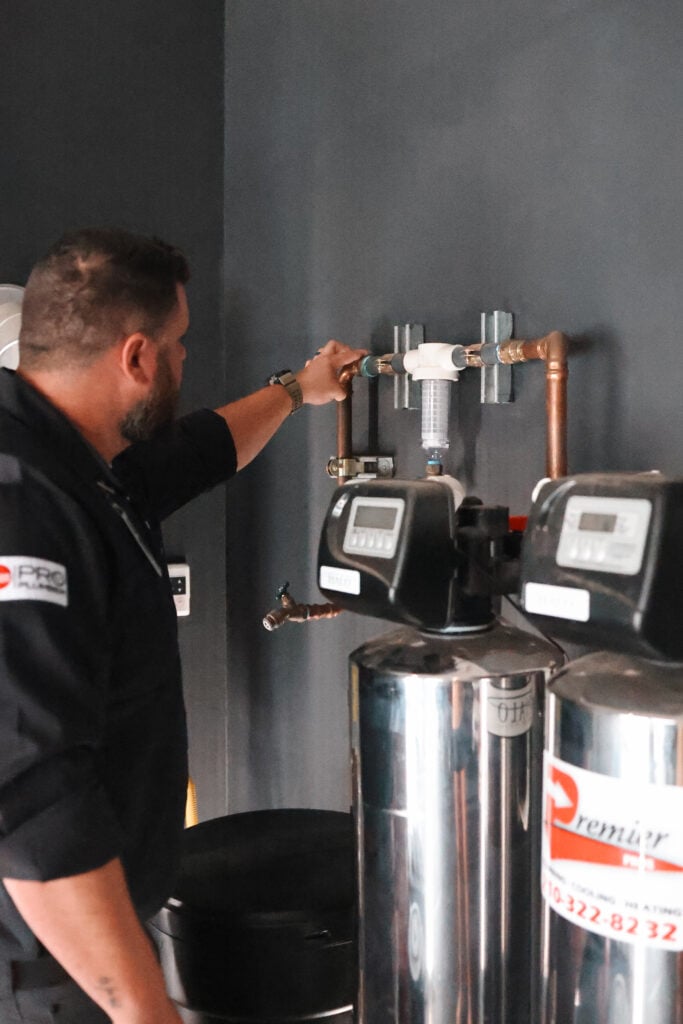 Premier Pros plumber adjusting a water filtration system with copper pipes in a San Antonio home