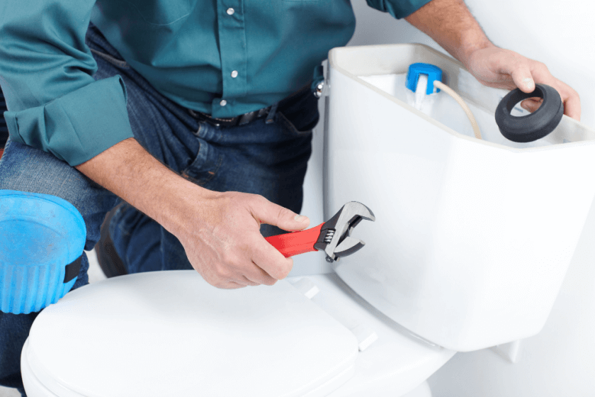 Plumber repairing a toilet in a clean bathroom