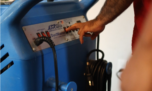 Industrial vacuum machine with HEPA filter sucking dust and debris from an air duct, ensuring complete removal.